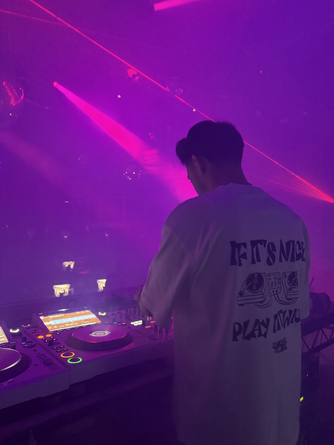 Panos DJing from behind in a pink-lit club